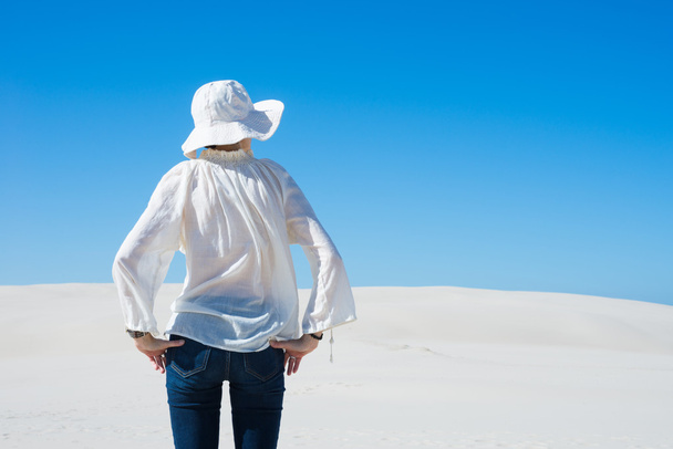 Nainen seisoo hiekkadyynillä ja katsoo poispäin
 - Valokuva, kuva