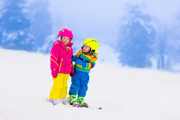 zwei Kinder beim Skifahren in den verschneiten Bergen - Foto, Bild