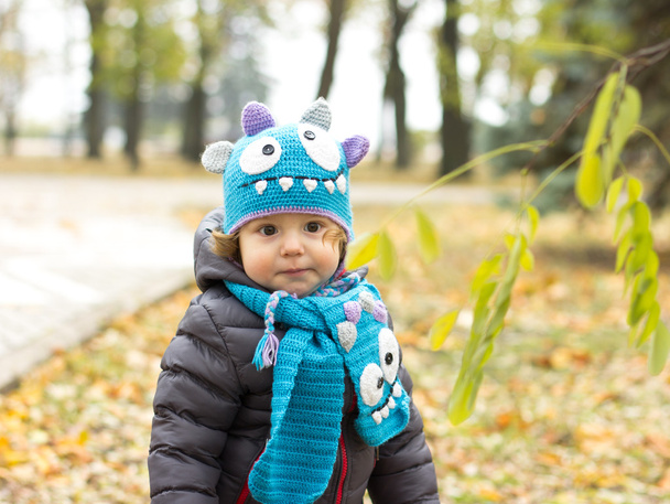 Gelukkig baby in een grappige hoed op een vrije loop. Wandelen buiten in de herfst. Herfstbladeren - Foto, afbeelding