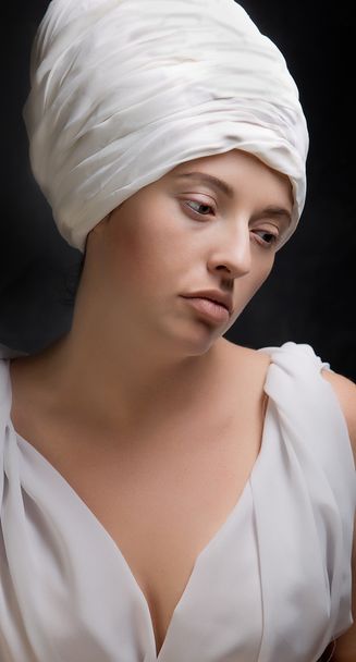 Pregnant woman dressed in a turban and draped in white fabric. - 写真・画像