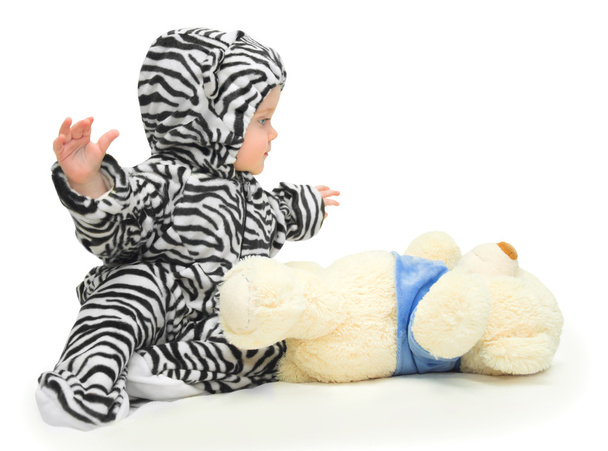 klein meisje in een gestreepte pak en gevuld speelgoed - Foto, afbeelding