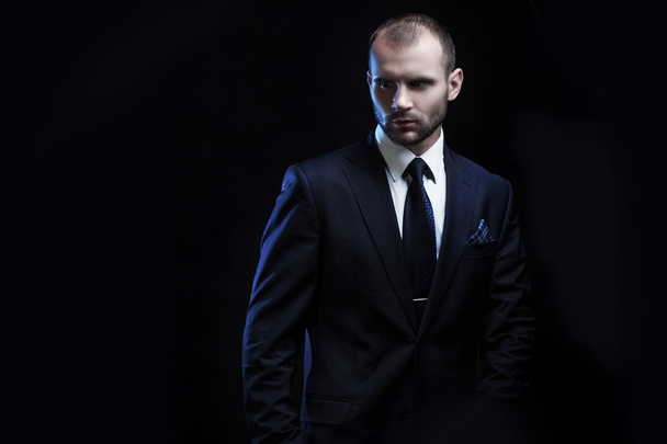 serious man in a business suit, dark background, backlight blue tones - Photo, image