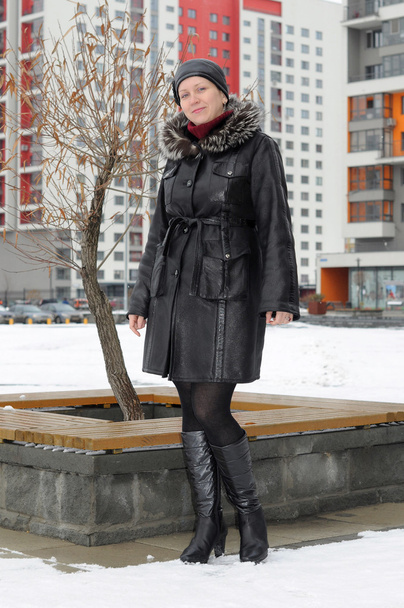 The woman in a sheepskin coat costs against new buildings - Фото, изображение