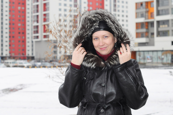 The woman in a sheepskin coat costs against new buildings - Fotoğraf, Görsel