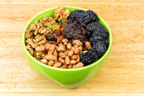 Mix nuts and dry fruits in plate on wooden background - Photo, Image
