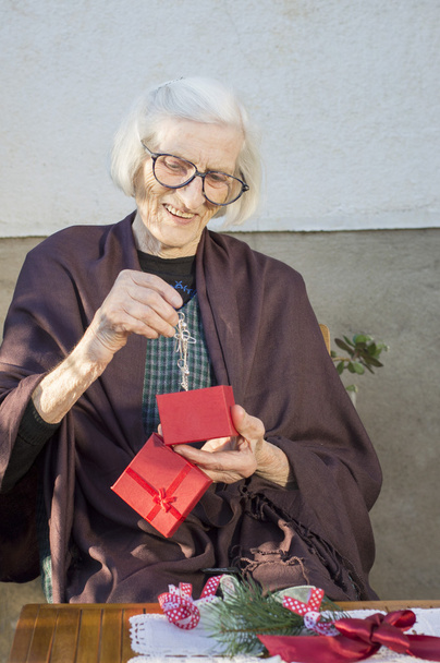 Старшая женщина смотрит на свой рождественский подарок
 - Фото, изображение