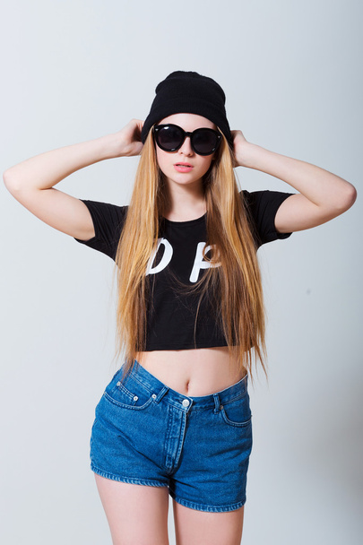 Portrait of beautiful sexy young girl in jeans shorts and sun glasses on white background - Foto, Bild