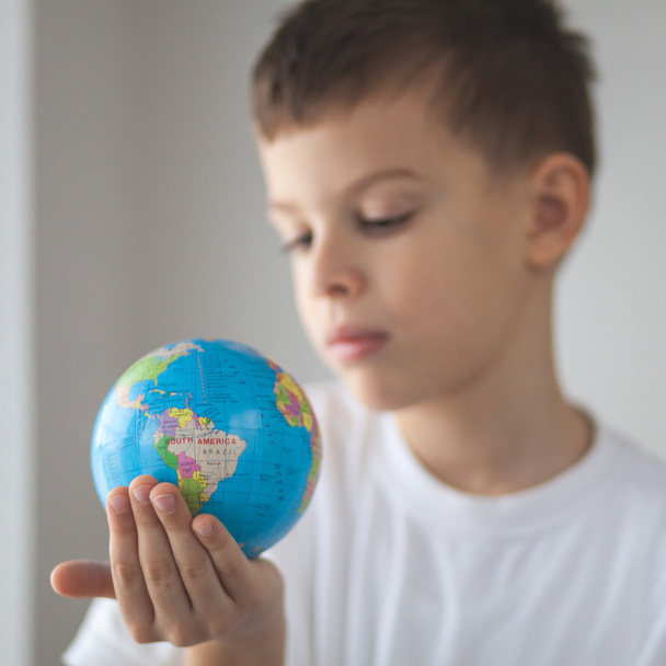 Un enfant tenant un jouet globus dans sa main. Jour lumière de fenêtre naturelle
 - Photo, image