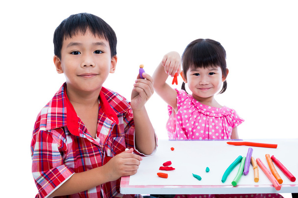 アジアの子供たちと一緒に遊んでは、テーブルで粘土を再生します。子供の想像力を強化します。 - 写真・画像