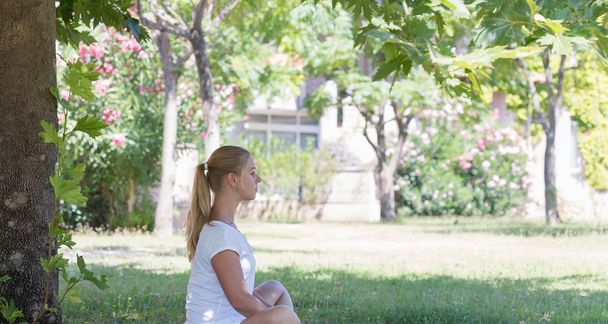 Une jeune femme blonde qui fait du yoga dans le parc
 - Photo, image