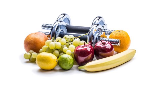 Dumbbells surrounded with healthy fruits measuring tape on a  white background with shadows. - Valokuva, kuva