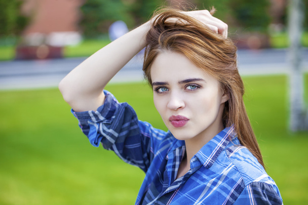 Close up of young beautiful woman in a checkered blue shirt - Foto, afbeelding