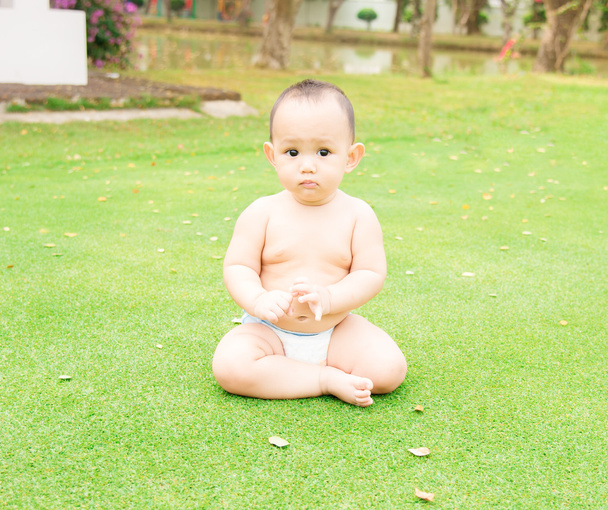 a little Thai baby sitting on the green grass field at the outdo - Foto, imagen