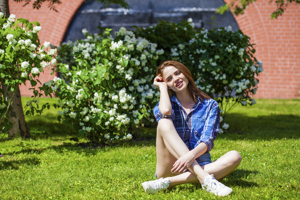 Young beautiful brown-haired woman sitting on the lawn - Foto, afbeelding