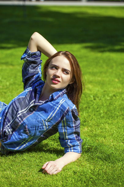 junge schöne Frau mit braunen Haaren auf dem Rasen liegend - Foto, Bild
