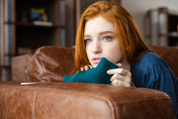 Pretty pensive redhead girl lying on sofa and thinking - Фото, зображення
