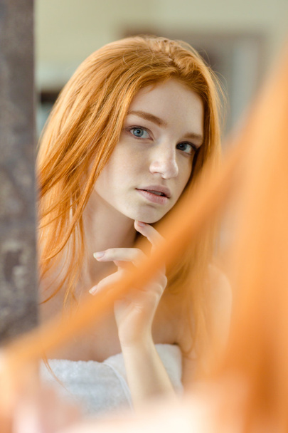 Γυναίκα κοκκινομάλλα κοιτάζοντας το είδωλό του στον καθρέφτη  - Φωτογραφία, εικόνα