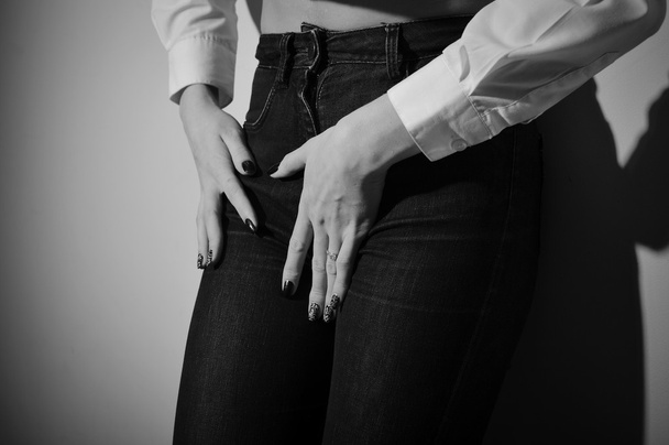 Seductive female wearing jeans long sleeve short and trousers on light background. Black and white photography - Fotoğraf, Görsel