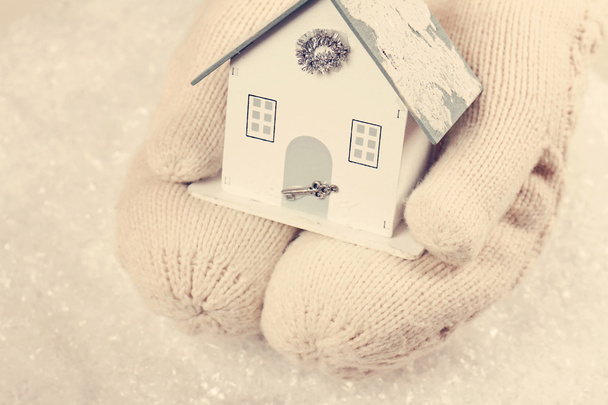 Mãos femininas em branco de malha luvas acolhedoras segurando casa bonito em
 - Foto, Imagem