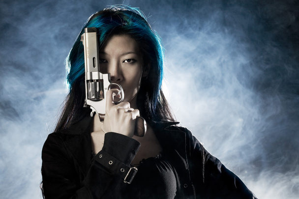 asiatische Schönheit hält Pistole mit Rauch - Foto, Bild