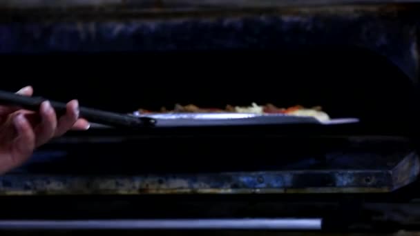 Closeup rukou šéfkuchaře Baker v bílé uniformě pizzu v kuchyni. Pizza se peče v tradiční dřevo pece na pizzu v restauraci. Šéfkuchař připravující pizzu v gastronomických. Pizzerii - Záběry, video