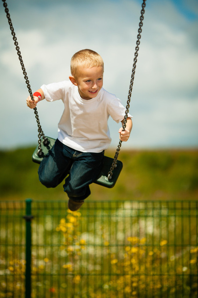 Little blonde boy child having fun on a swing outdoor - Photo, image