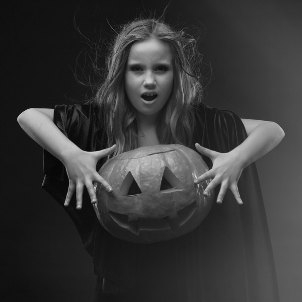 Little girl in halloween costume of the witch with the pumpkin make spell conjure - Фото, зображення