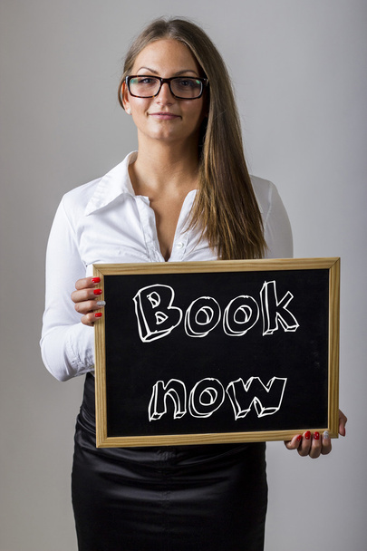 Book now - Young businesswoman holding chalkboard with text - Fotografie, Obrázek