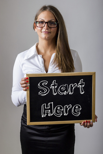 Start Here - Young businesswoman holding chalkboard with text - 写真・画像