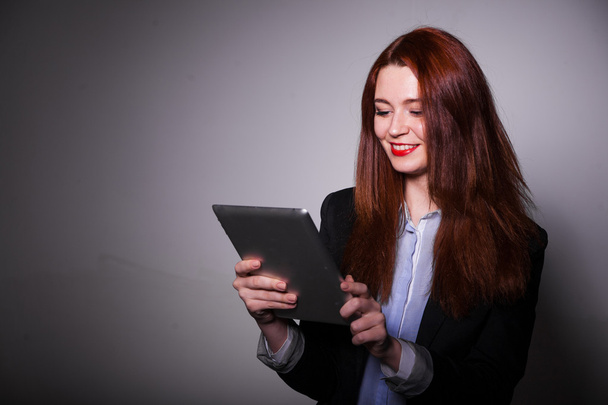 haired smiling girl using tablet over gray background - Foto, Imagem