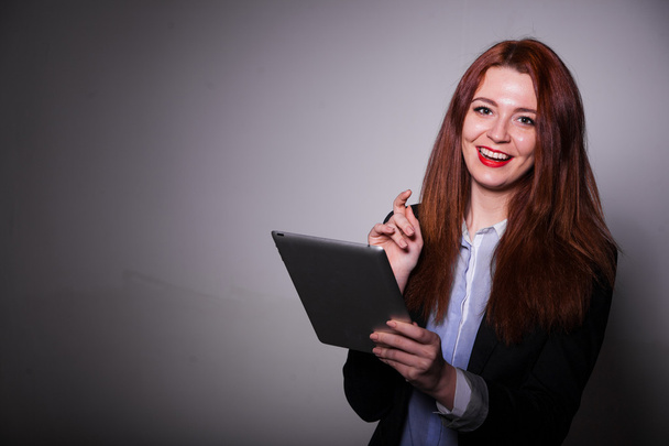 usměvavá brunetka pomocí tabletu přes šedé pozadí - Fotografie, Obrázek