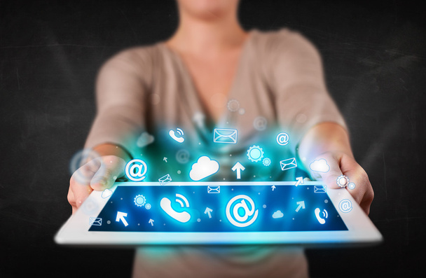 Persona sosteniendo una tableta con iconos y símbolos de tecnología azul - Foto, imagen