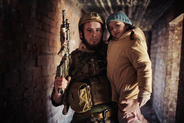 warrior with gun holding little girl - Foto, Imagen