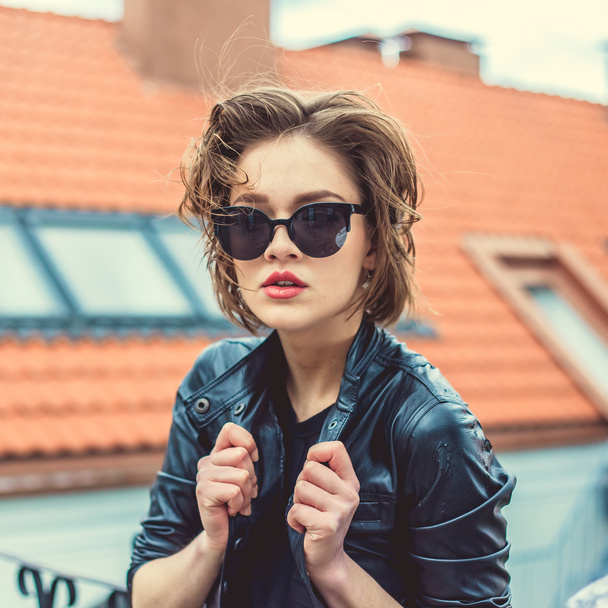 Stylish girl in the leather jacket and sunglasses outdoor portrait - Photo, image