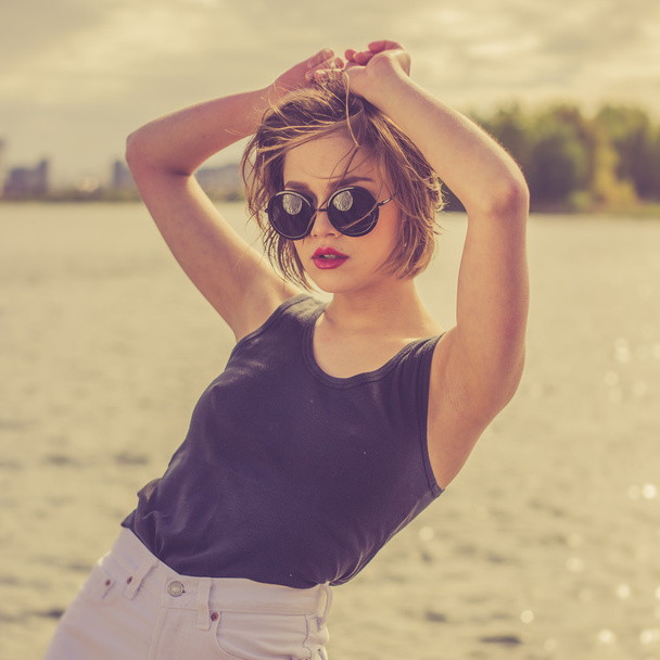 Menina sensual bonita nos óculos de sol perto de retrato de água
 - Foto, Imagem
