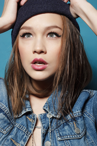 Closeup studio shot of pretty hipster teenage girl with beanie hat wearing jeans jacket looking at camera posing. - Fotó, kép
