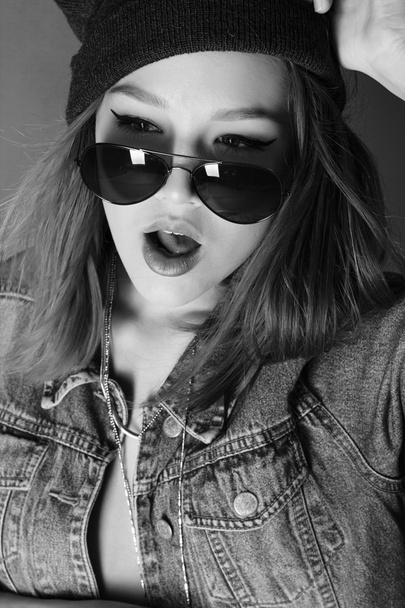 Stylish vogue rock girl in the jeans hat and sunglasses black and white portrait in the studio - 写真・画像