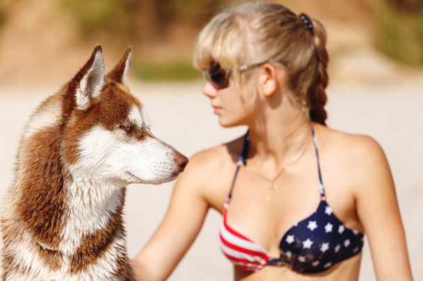 Nuori tyttö istuu rannalla koiran kanssa
 - Valokuva, kuva