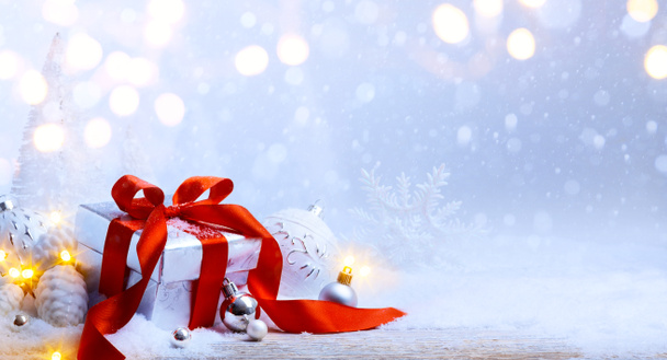 Рождественские шары и подарочная коробка на снегу
 - Фото, изображение
