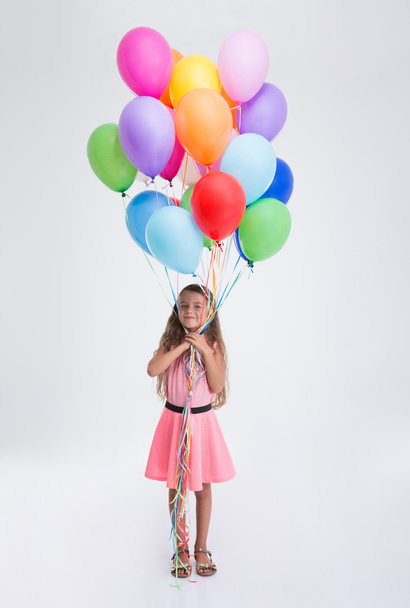 Happy little girl standing with balloons - Фото, изображение