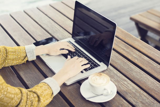Girl with laptop and cup of coffee on wooden table - Photo, Image