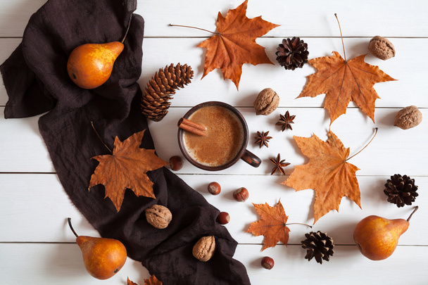 Autumn composition with hot cup coffee cinnamon, scarf, nuts and leaves. Concept of cozy morning, comfort, relax, melancholy, fall weather, home. Vintage white table background. - 写真・画像