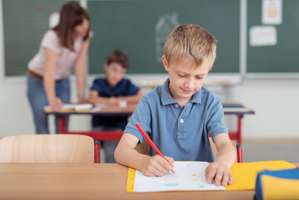 Young boy sitting writing notes at school - Φωτογραφία, εικόνα