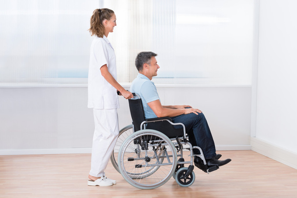 Doctor Pushing Disabled Patient On The Wheelchair - Foto, Imagen