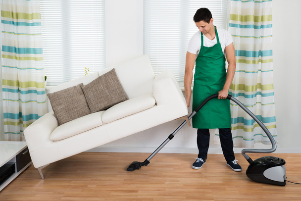 Man Lifting Couch While Cleaning Floor - Foto, Bild