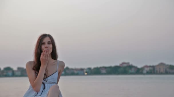 Beautiful girl in a white sundress blows a kiss to the camera - Felvétel, videó