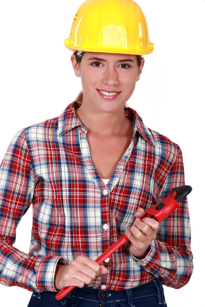 Smiling tradeswoman holding a pipe wrench - Zdjęcie, obraz