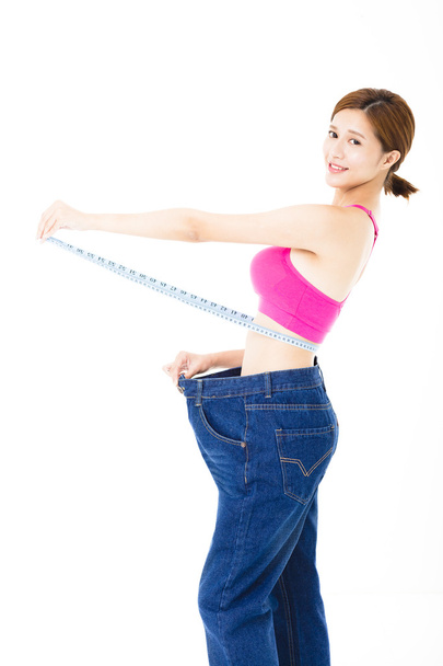 jovem mulher magra com fita métrica e jeans grandes
 - Foto, Imagem
