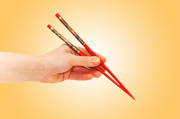 Hand holding choipsticks on gradient - Photo, Image