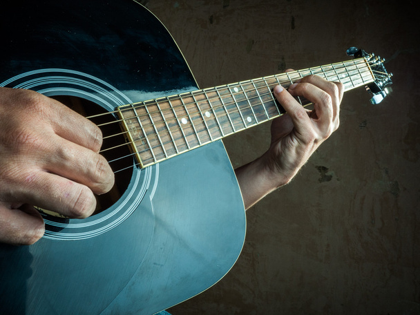 Closeup photo of an acoustic guitar played by a man. - Photo, Image
